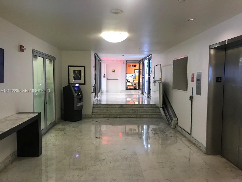 Lobby area featuring polished stone flooring, a stainless steel elevator, and a built-in stone-top console table