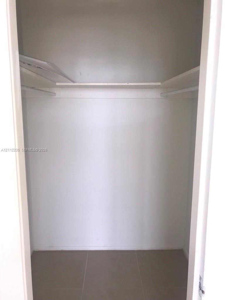 Interior closet featuring ceramic tile flooring, upper storage shelving, and integrated hanging rods