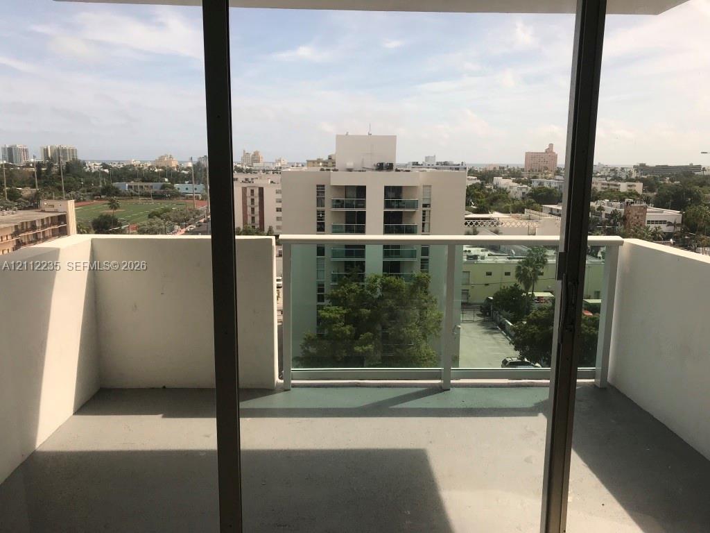 Private balcony featuring concrete flooring, solid side walls, and a glass-panel railing