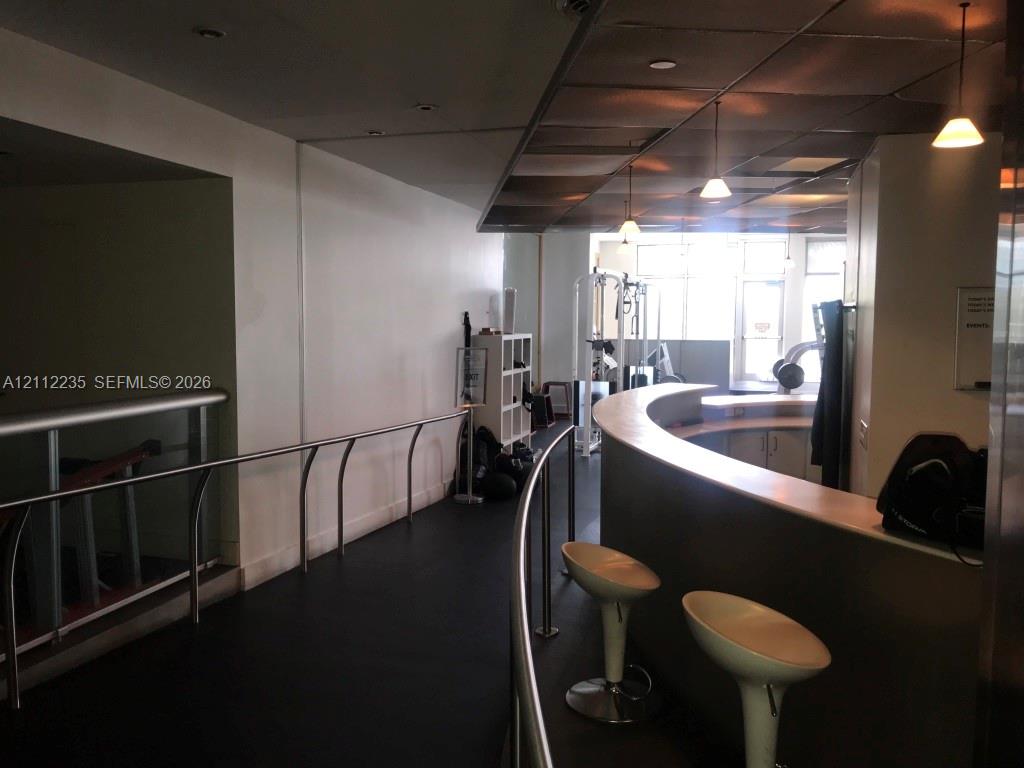 Curved built-in counter with solid surface top, metal handrail, pendant lighting, recessed ceiling lights, and resilient flooring