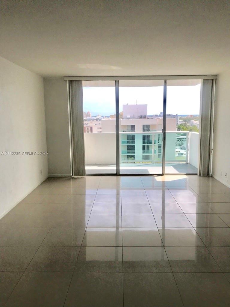 Living area featuring large-format tile flooring and full-height sliding glass doors opening to a private balcony