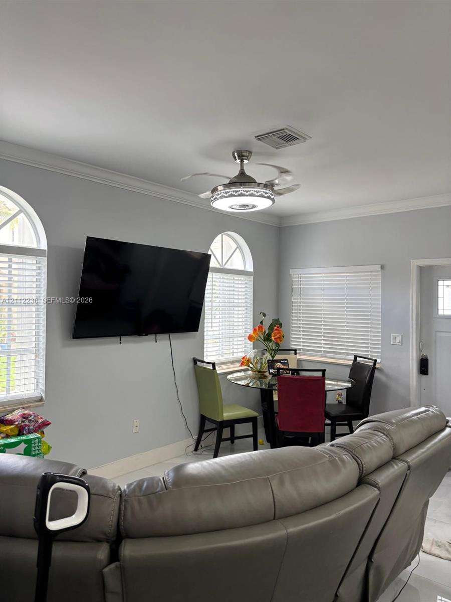 Interior room featuring arched windows, horizontal blinds, and a retractable blade ceiling fan with integrated lighting