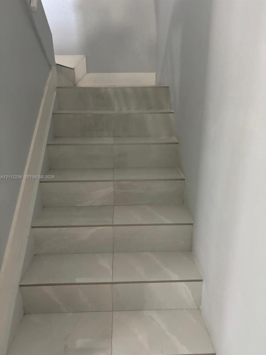 Staircase finished with large-format light-toned tile featuring subtle veining, complemented by smooth painted walls