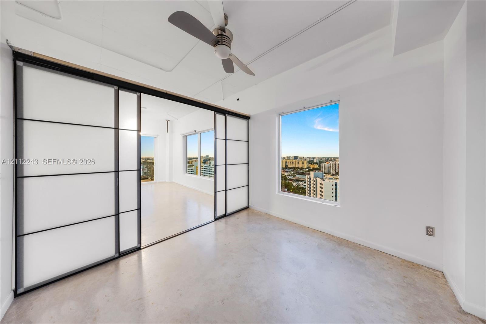 Interior space featuring polished concrete flooring, sliding frosted glass partitions with black frames, and an integrated ceiling fan