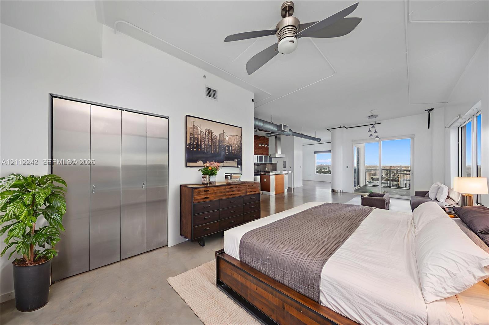 Industrial-style space featuring high ceilings, concrete flooring, stainless steel closet doors, exposed ductwork, and a built-in ceiling fan