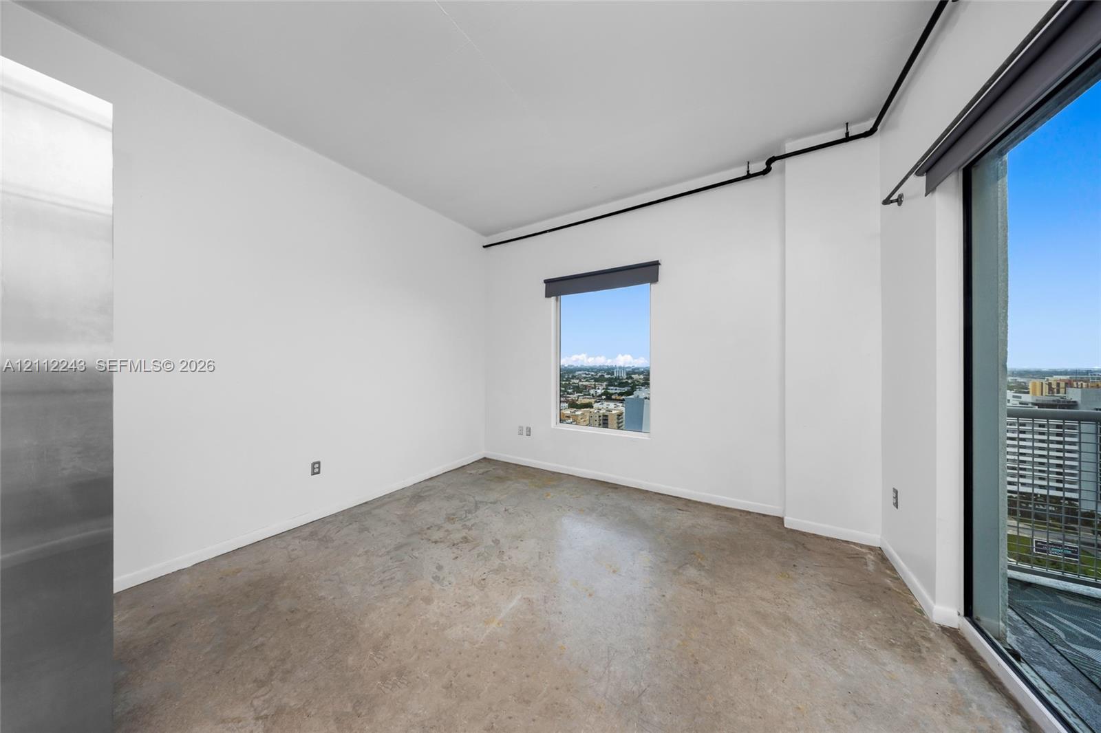 Polished concrete flooring, high ceilings with industrial-style exposed piping, and oversized windows providing natural light