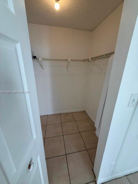 Walk-in storage space featuring ceramic tile flooring, neutral-toned walls, and installed wire shelving