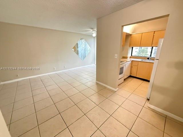 Neutral-toned ceramic tile flooring, kitchen featuring light-toned cabinetry and a window, and wall-mounted diamond-shaped mirror