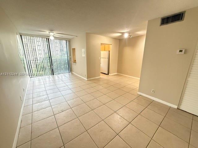 Open interior featuring neutral tile flooring, sliding glass doors with vertical blinds, and a built-in wall niche