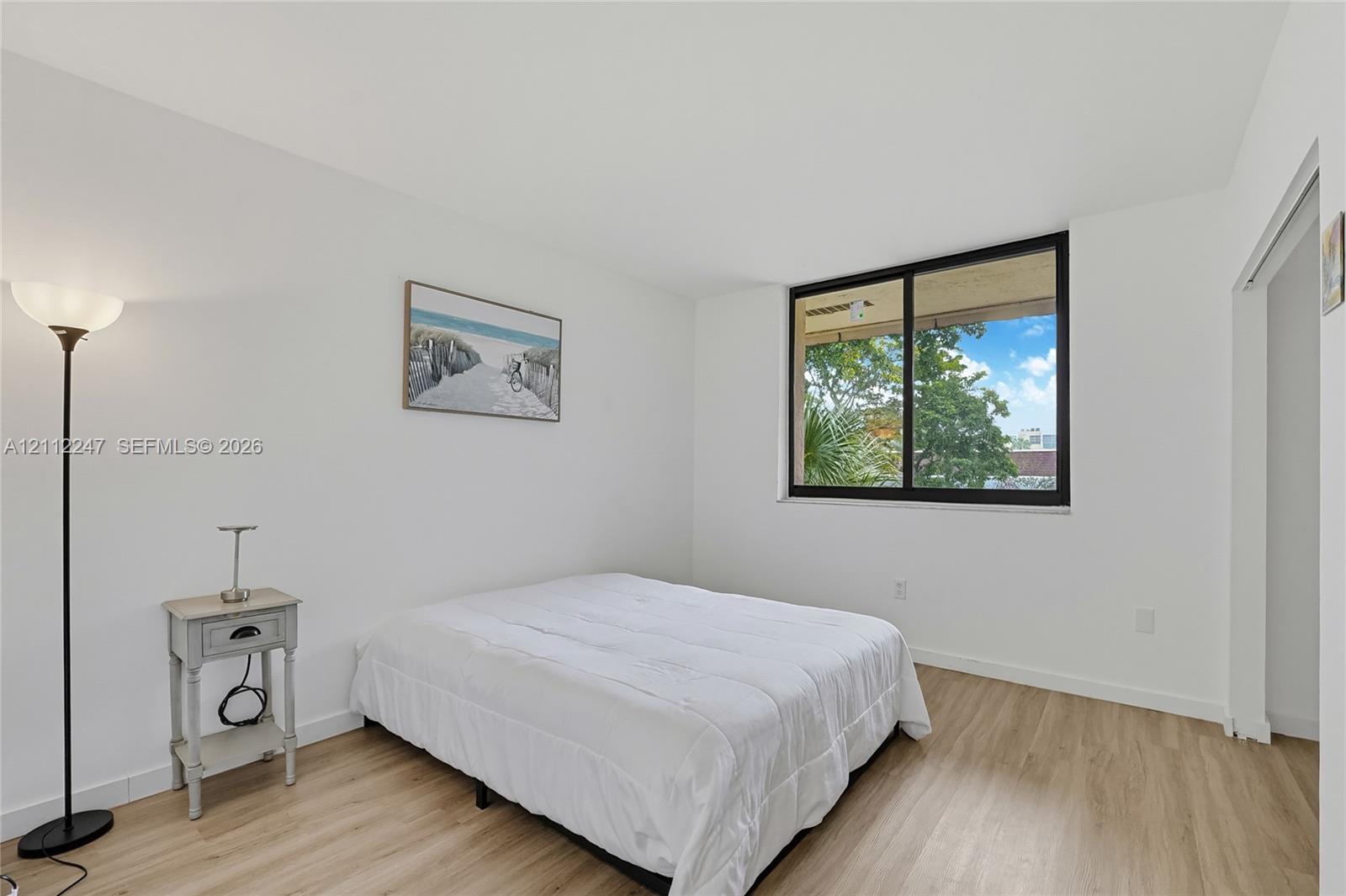 Interior space featuring wood-finish flooring, neutral walls, and a large window with black framing