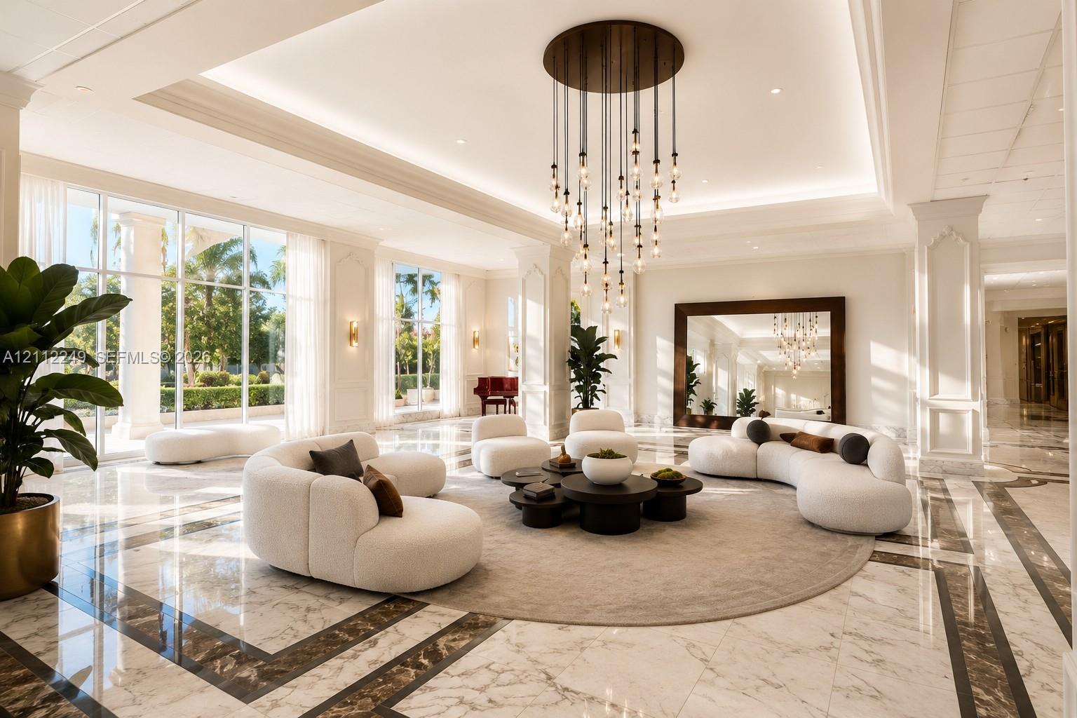 Grand lobby featuring polished stone flooring with intricate inlaid borders, floor-to-ceiling windows, tiered modern pendant lighting, and recessed ceiling coffers