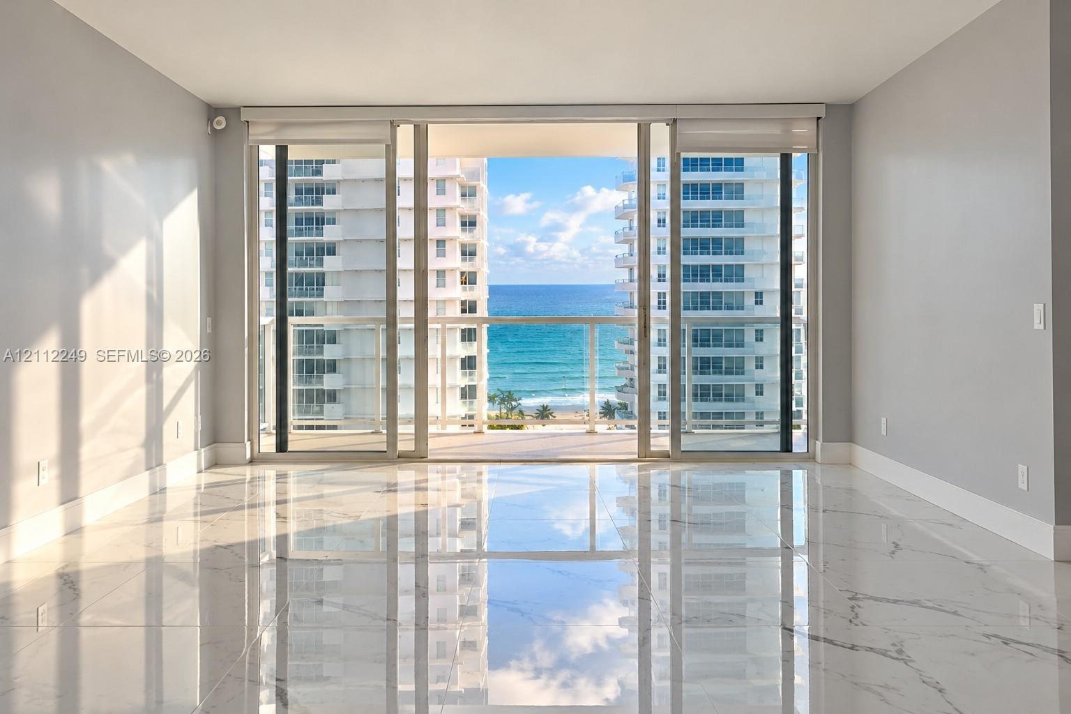 Polished stone flooring, floor-to-ceiling sliding glass doors, and a glass-paneled balcony overlooking the ocean Polished stone flooring, floor-to-ceiling sliding glass doors, and a glass-paneled balcony overlooking the ocean