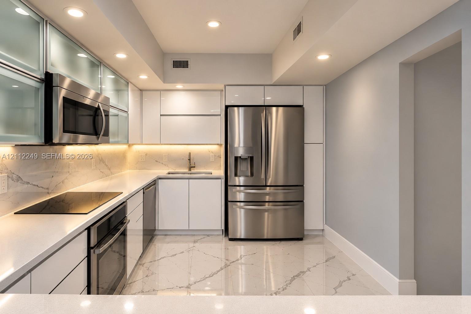 Contemporary kitchen featuring high-gloss cabinetry, stainless steel appliances, white stone-finish countertops with matching backsplash, and polished stone-finish flooring