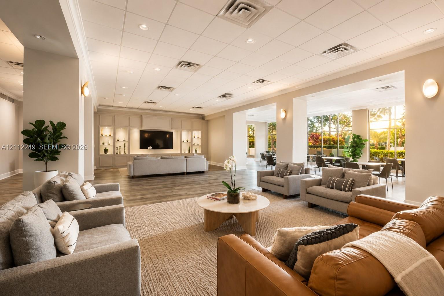 Expansive common area featuring wood-finish flooring, floor-to-ceiling windows, built-in recessed cabinetry, and integrated ceiling lighting