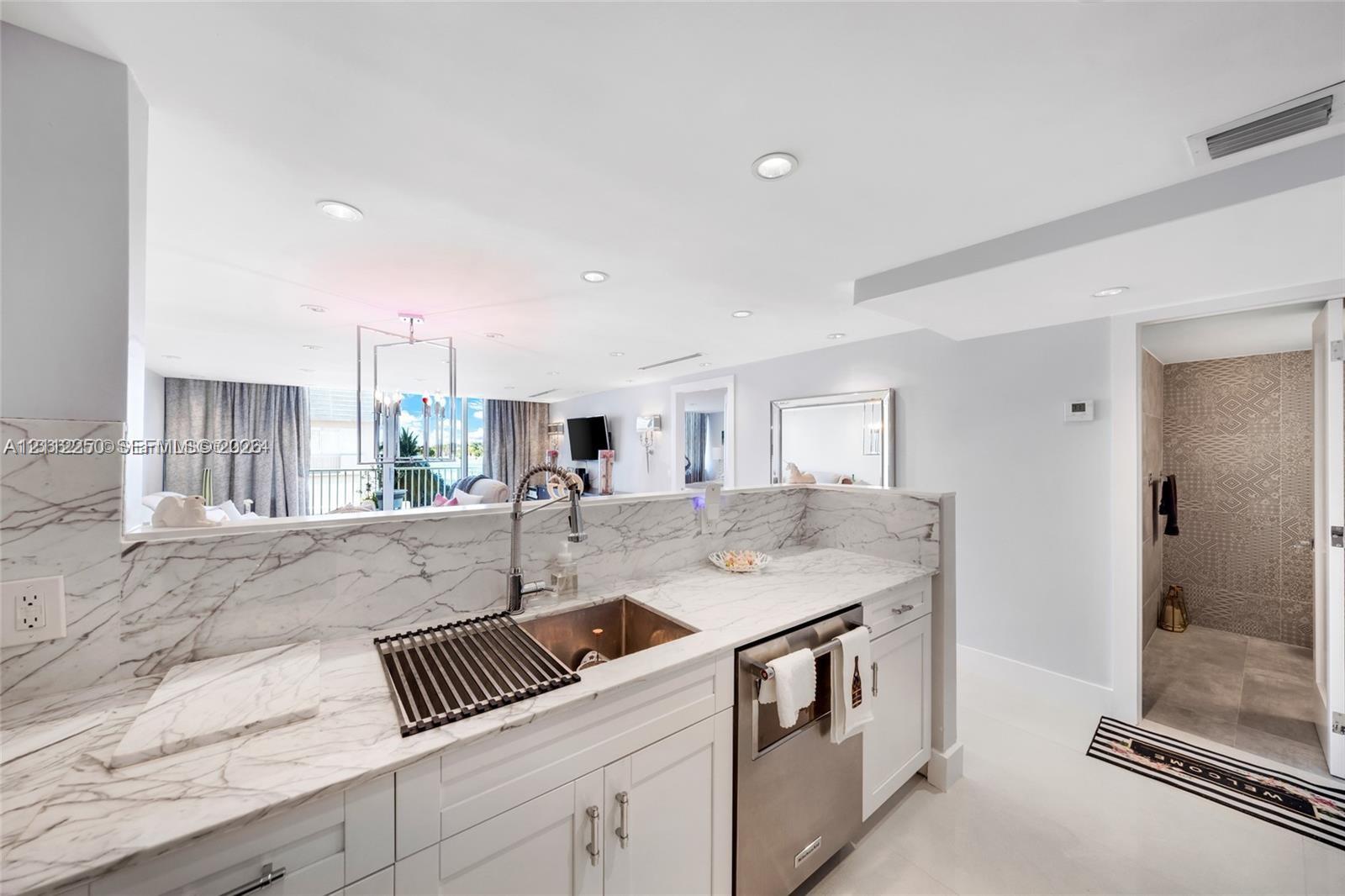 Kitchen featuring stone-patterned countertops, white cabinetry, a stainless steel undermount sink with a gooseneck faucet, and recessed lighting