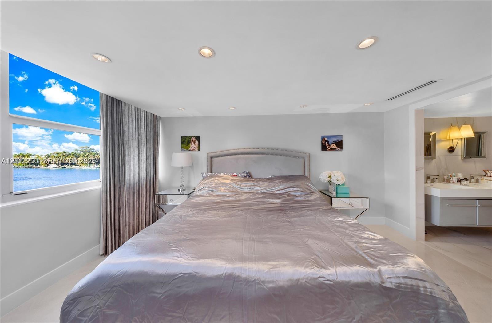 Waterfront exposure with expansive window, recessed ceiling lighting, and attached floating vanity with dual sinks