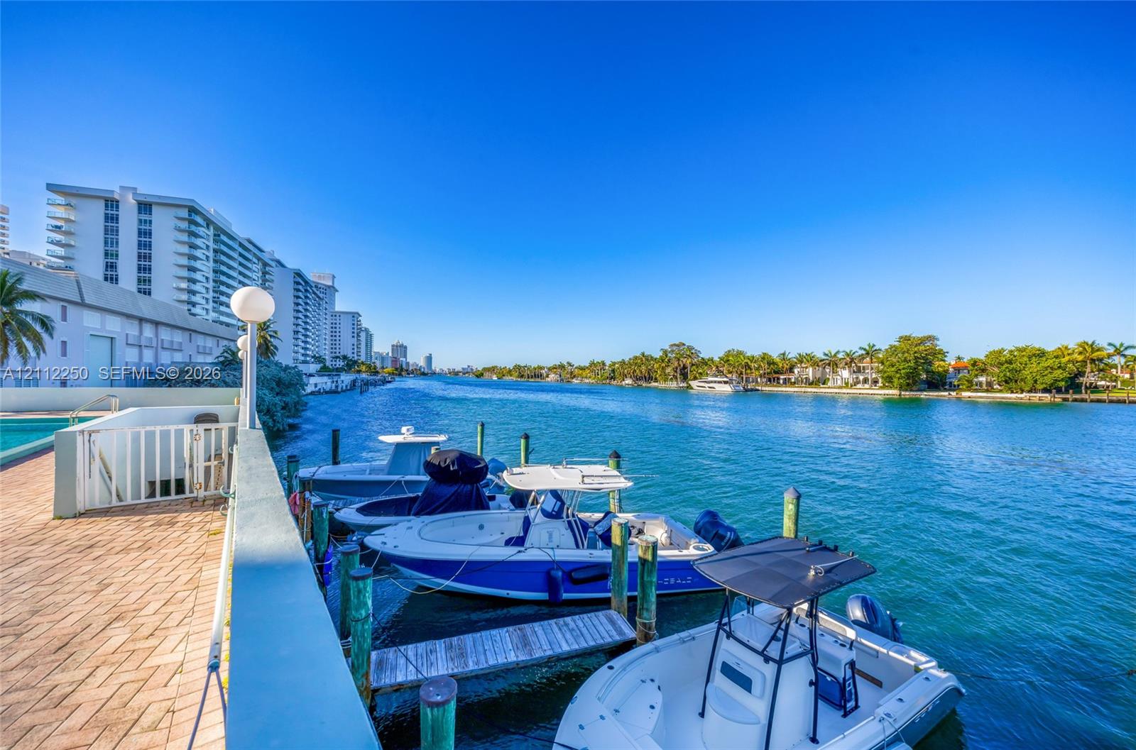 Waterfront bulkhead with brick-paver decking, private dock pilings, and direct deep-water access