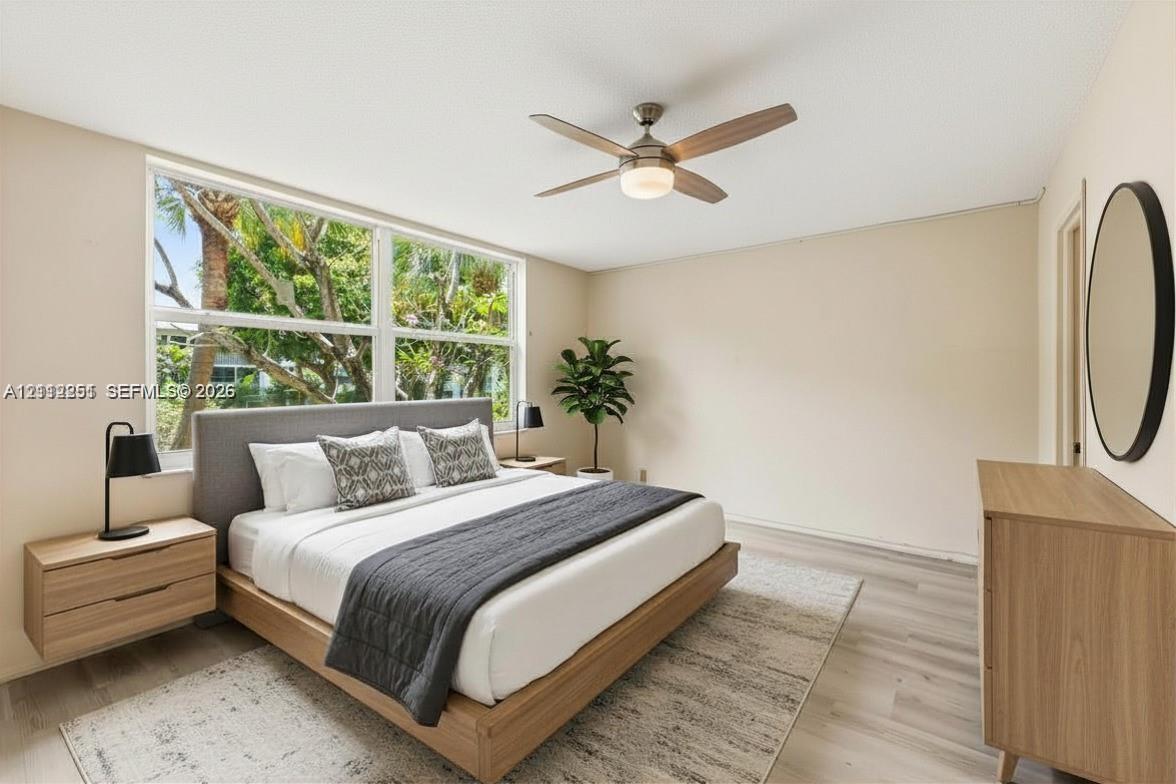 Wood-finish flooring, oversized picture windows, and a ceiling fan with integrated lighting Wood-finish flooring, oversized picture windows, and a ceiling fan with integrated lighting