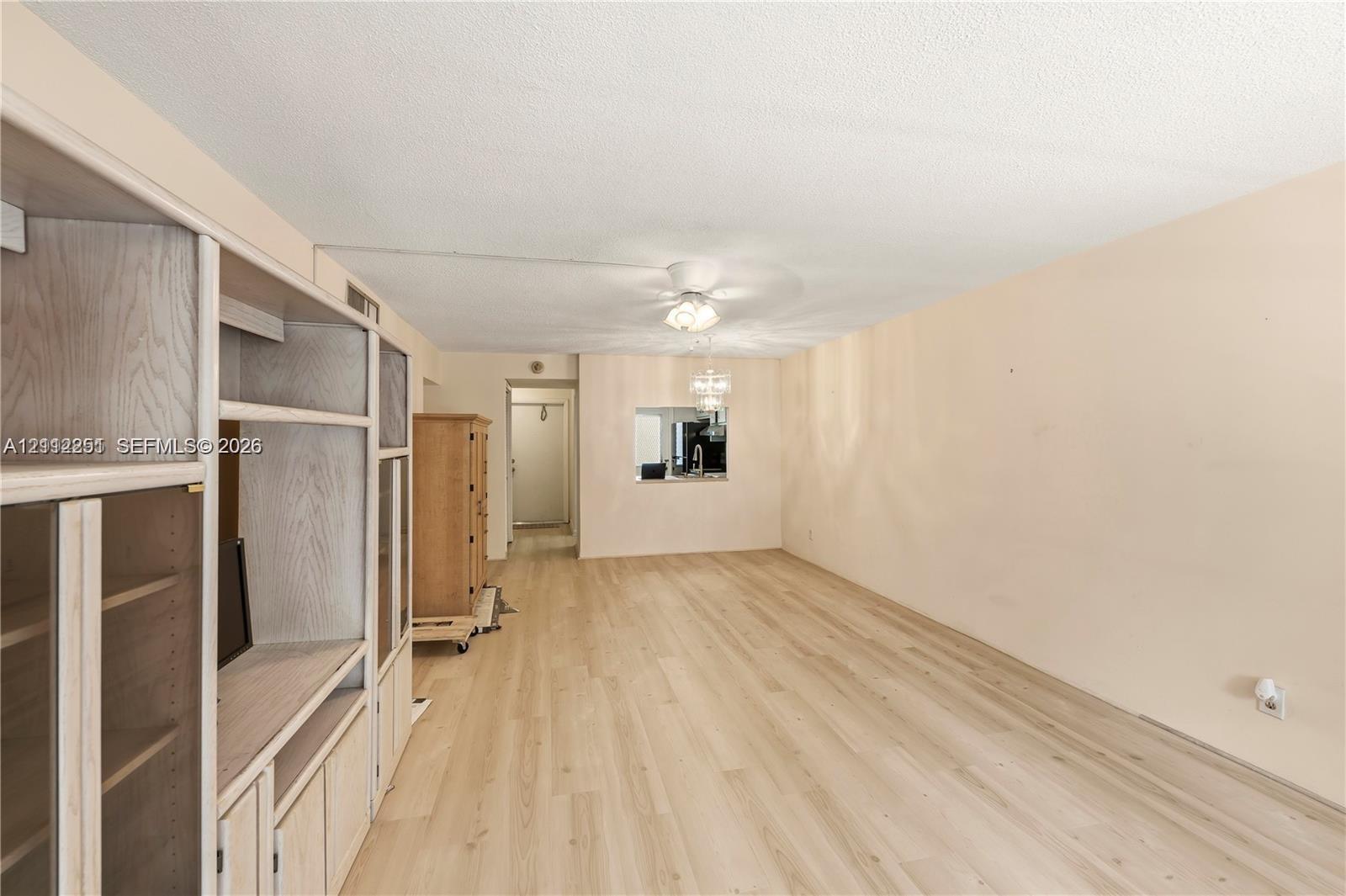 Light-toned wood-finish flooring, built-in floor-to-ceiling cabinetry, recessed ceiling fan with integrated lighting, and a pass-through window opening