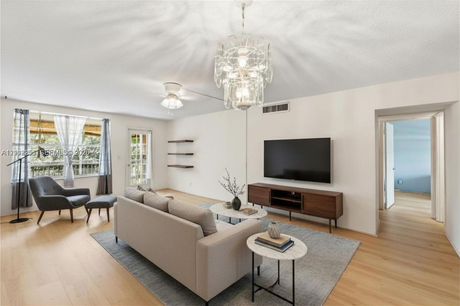 Living area featuring wood-finish flooring, a decorative multi-tiered chandelier, and three built-in wall shelves