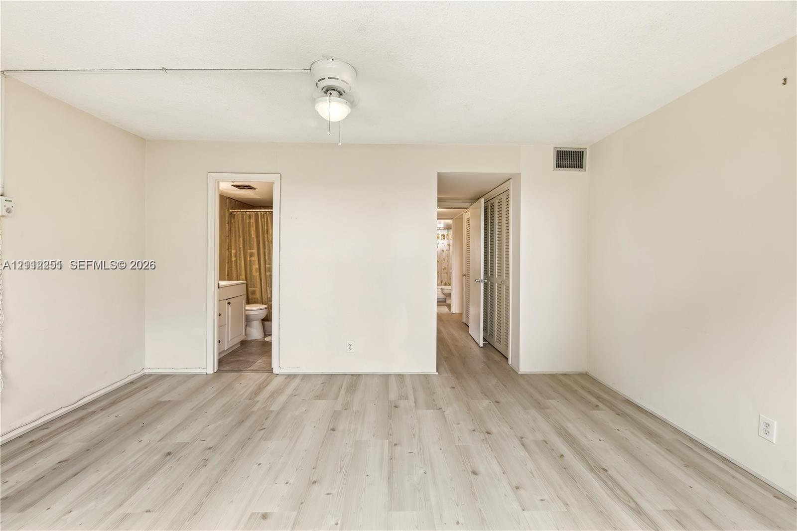 Interior room featuring wood-finish flooring, a ceiling-mounted light fixture with a fan, and bi-fold closet doors
