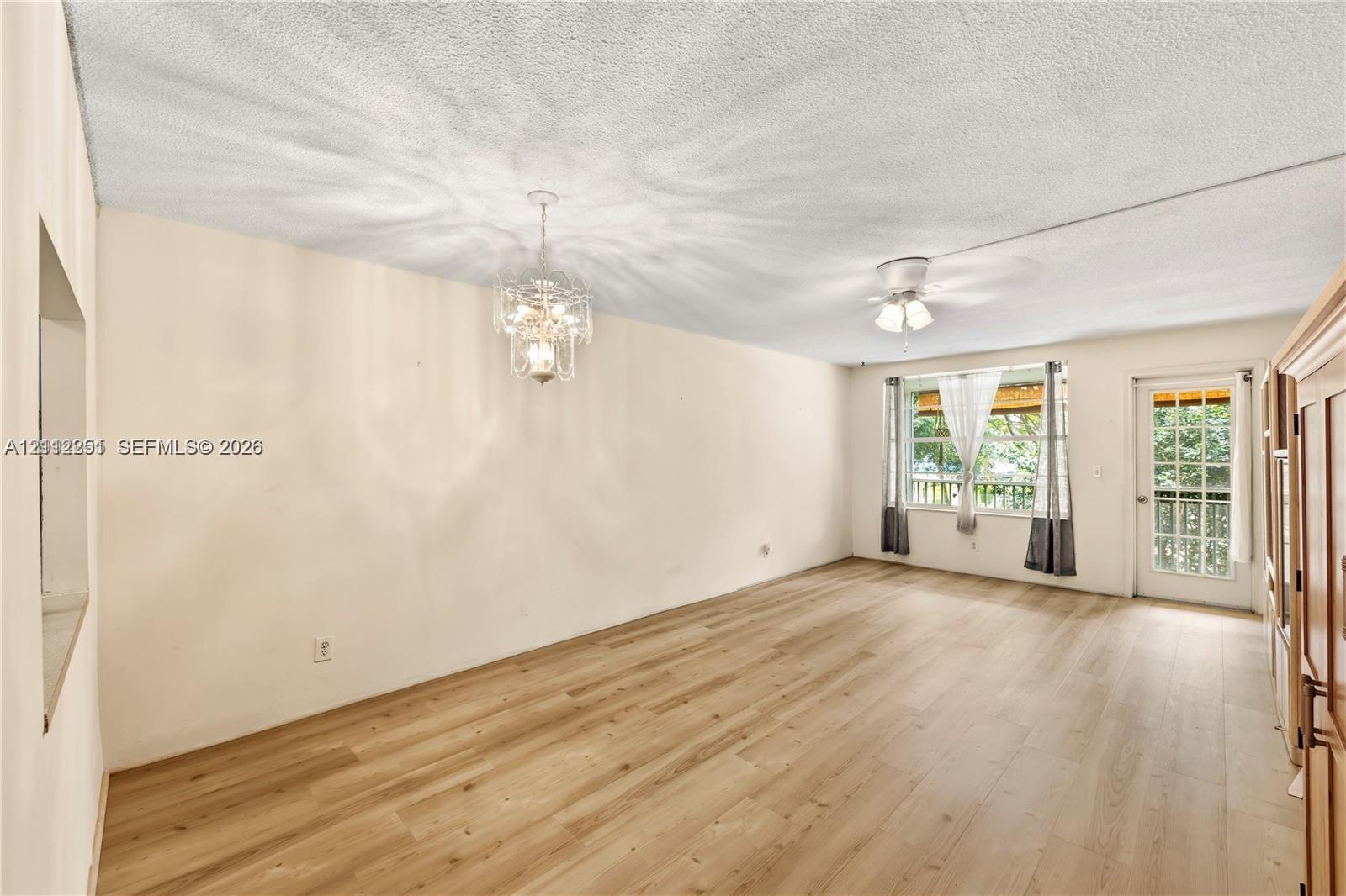 Interior space featuring wood-finish flooring, a decorative metal chandelier, a ceiling fan, and a glass-paneled exterior door