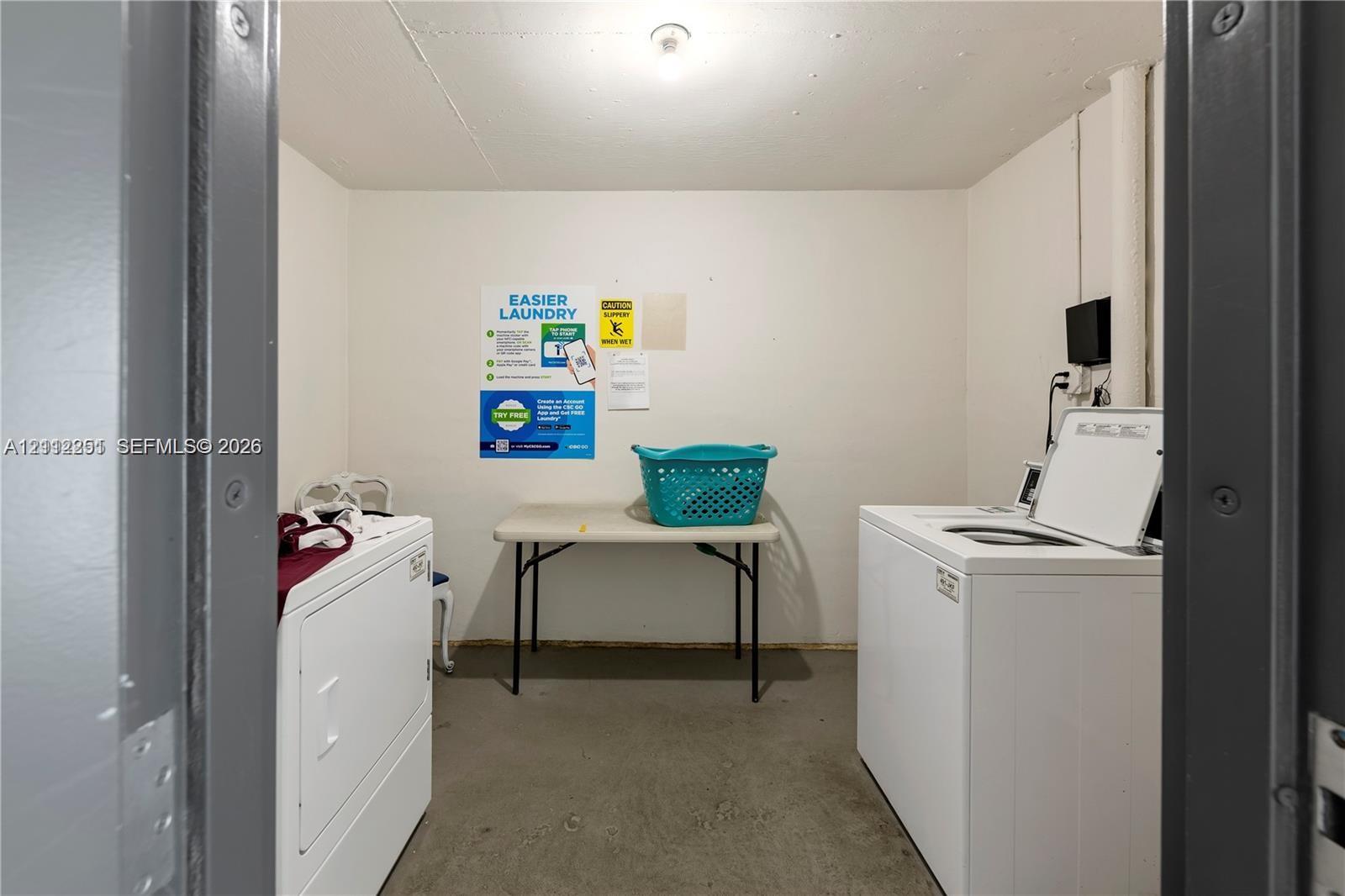 Dedicated laundry area featuring solid-surface flooring, neutral wall finishes, and overhead lighting