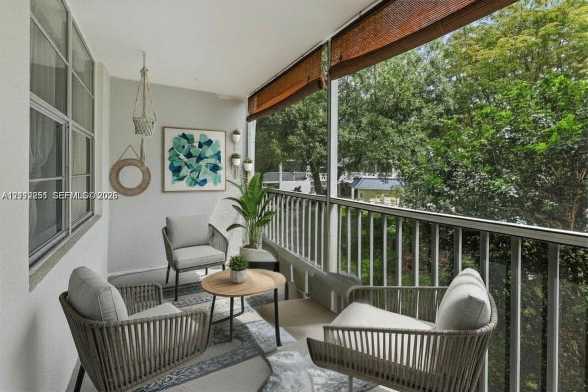 Screened balcony featuring a white metal railing, roll-up bamboo shade, and large-format tile flooring