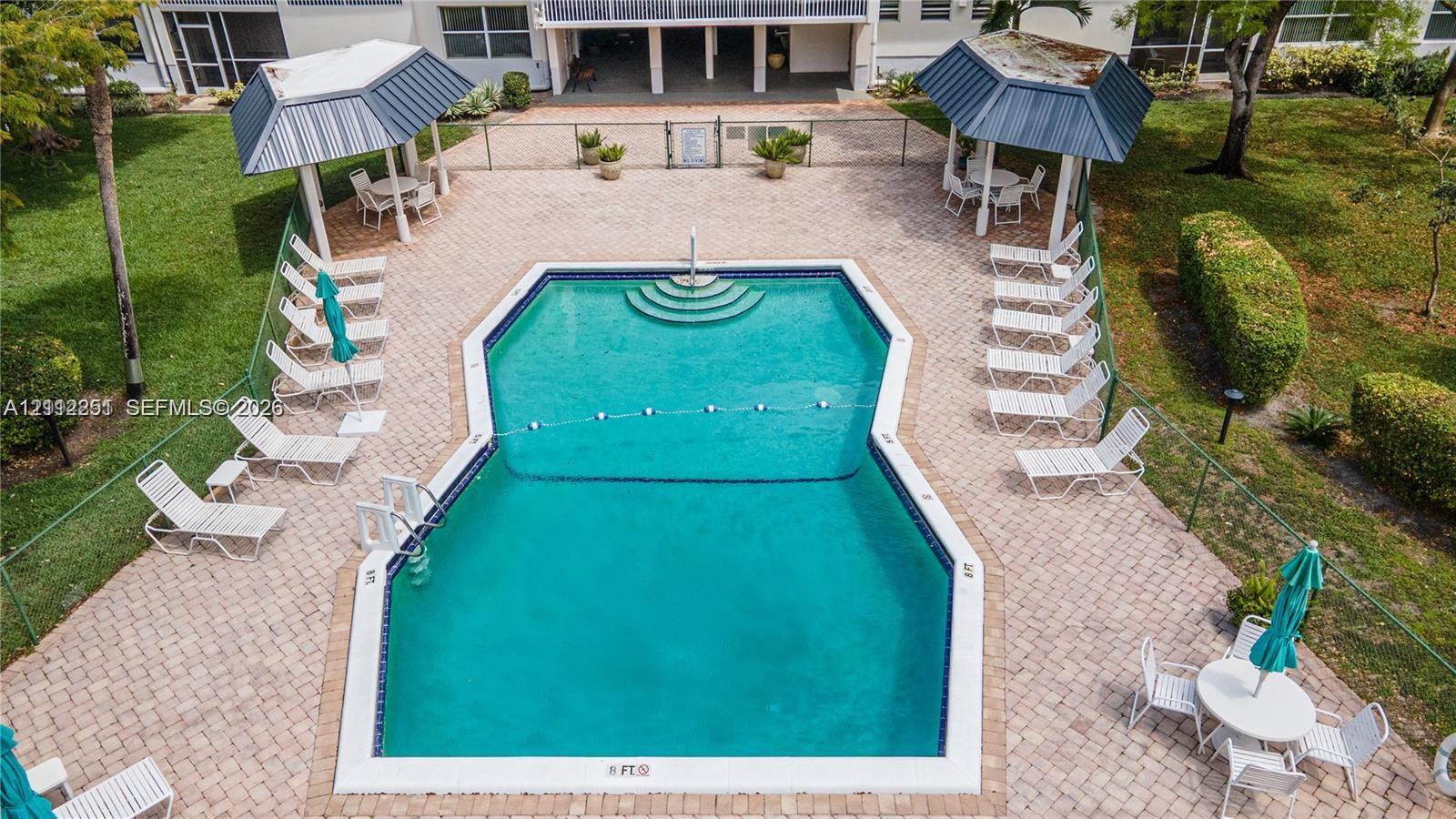 Community pool featuring paved decking, metal-roofed cabanas, and integrated stair entry