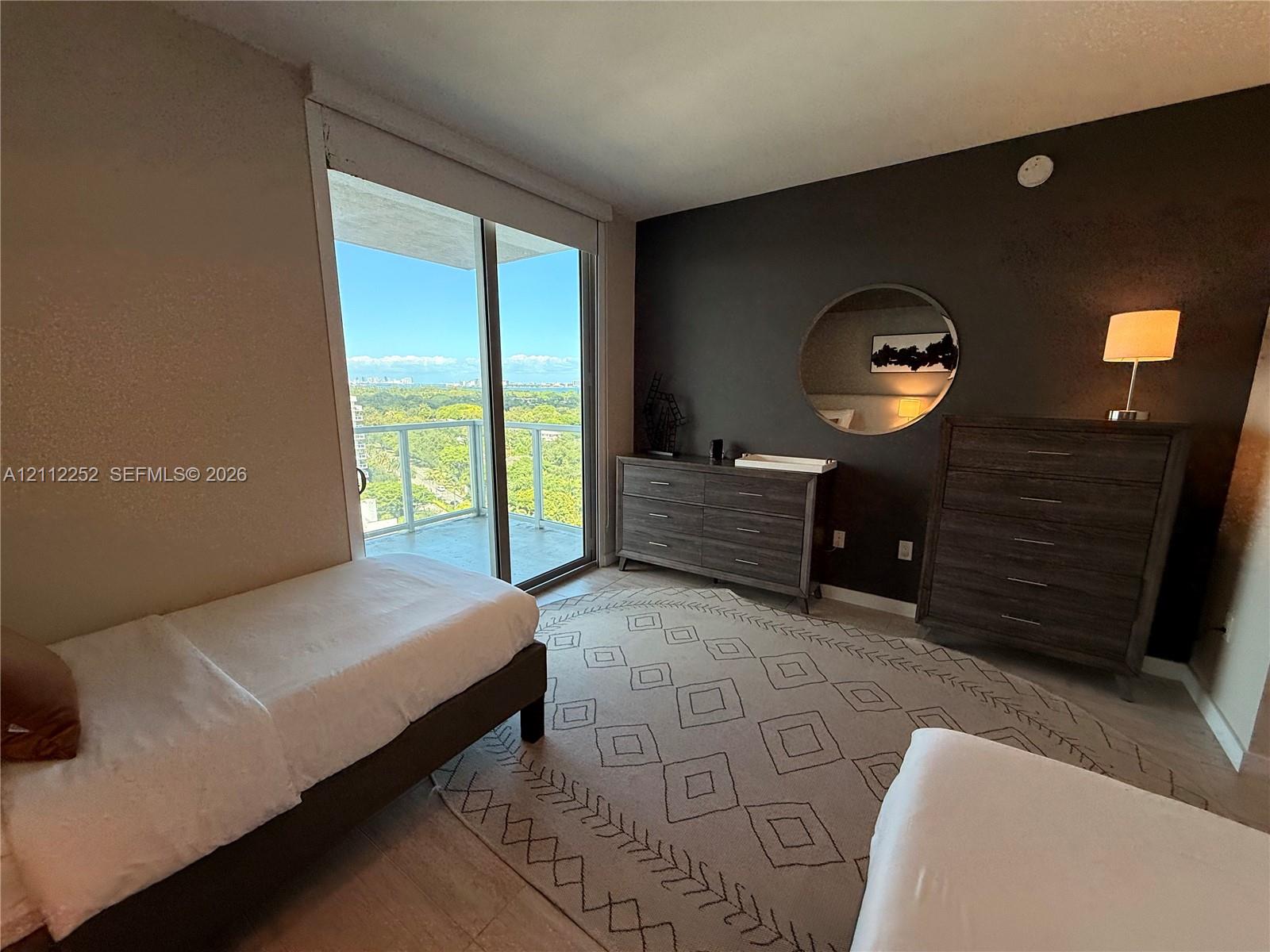 Floor-to-ceiling glass sliding door, balcony with glass railing, wood-finish flooring, and accent wall