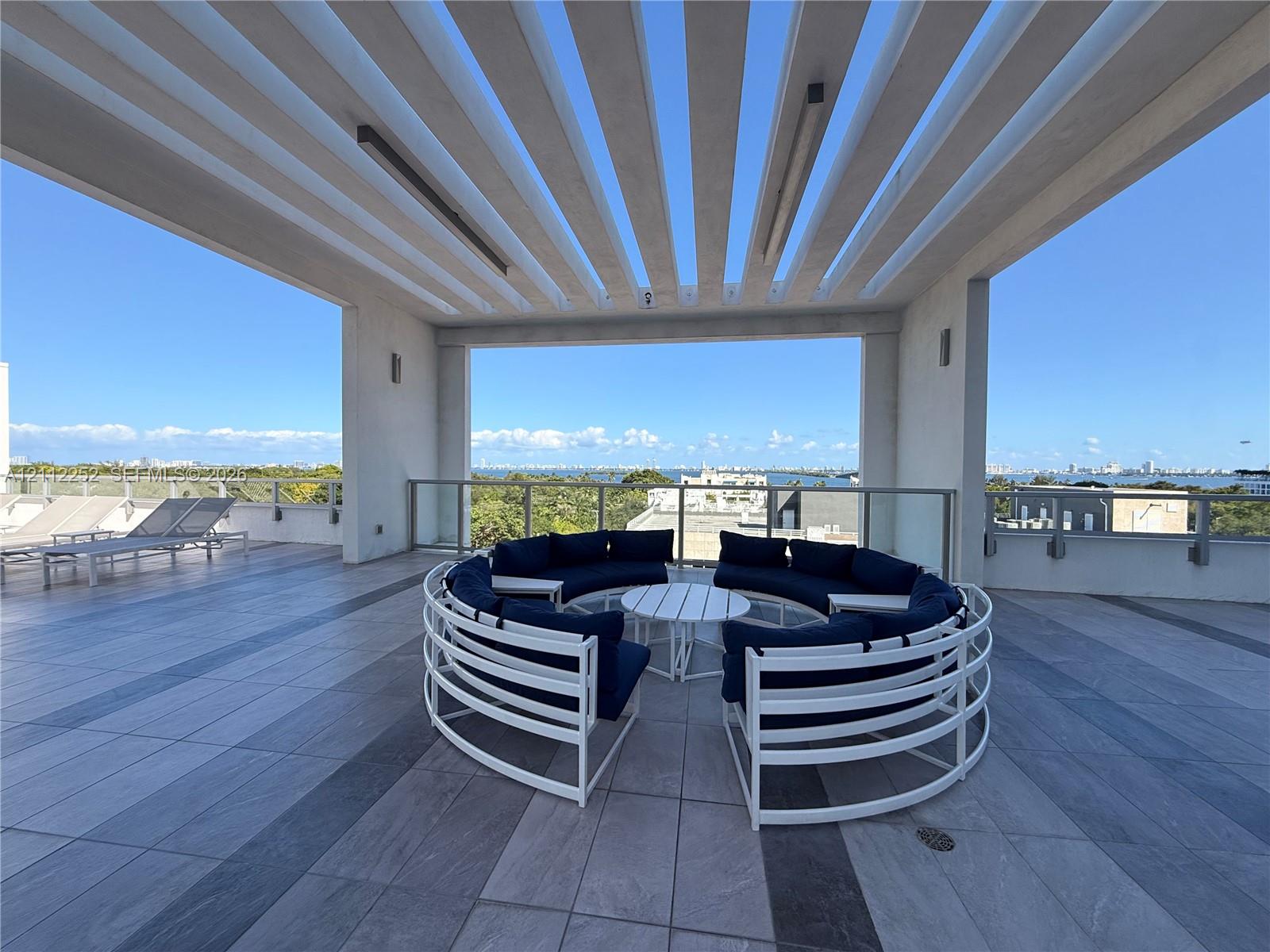 Expansive rooftop terrace featuring a structural pergola, large-format tile flooring, and glass railing enclosures