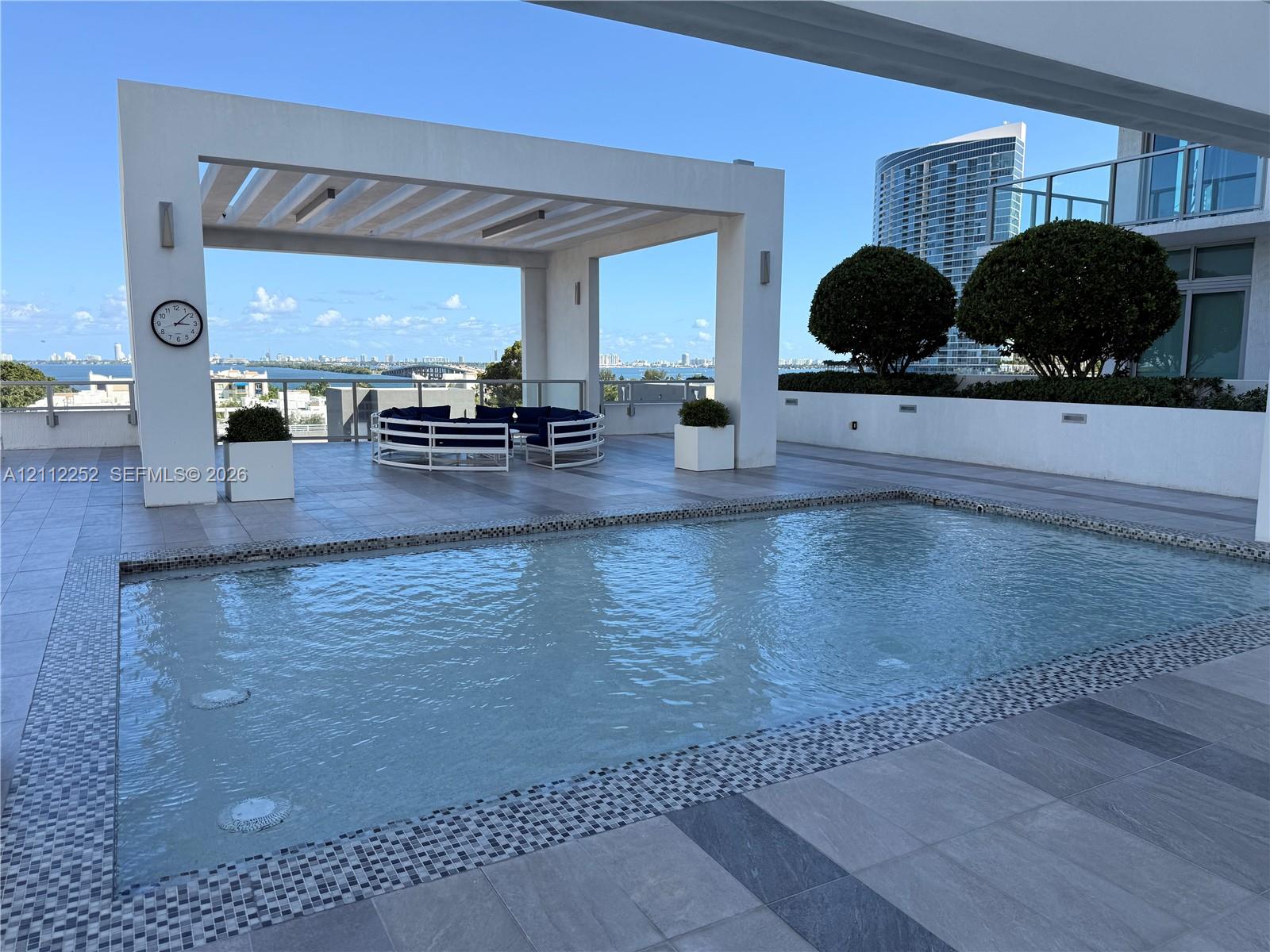 Terrace featuring a swimming pool with decorative mosaic tile trim, a structural pergola, large-format tile flooring, and integrated wall lighting