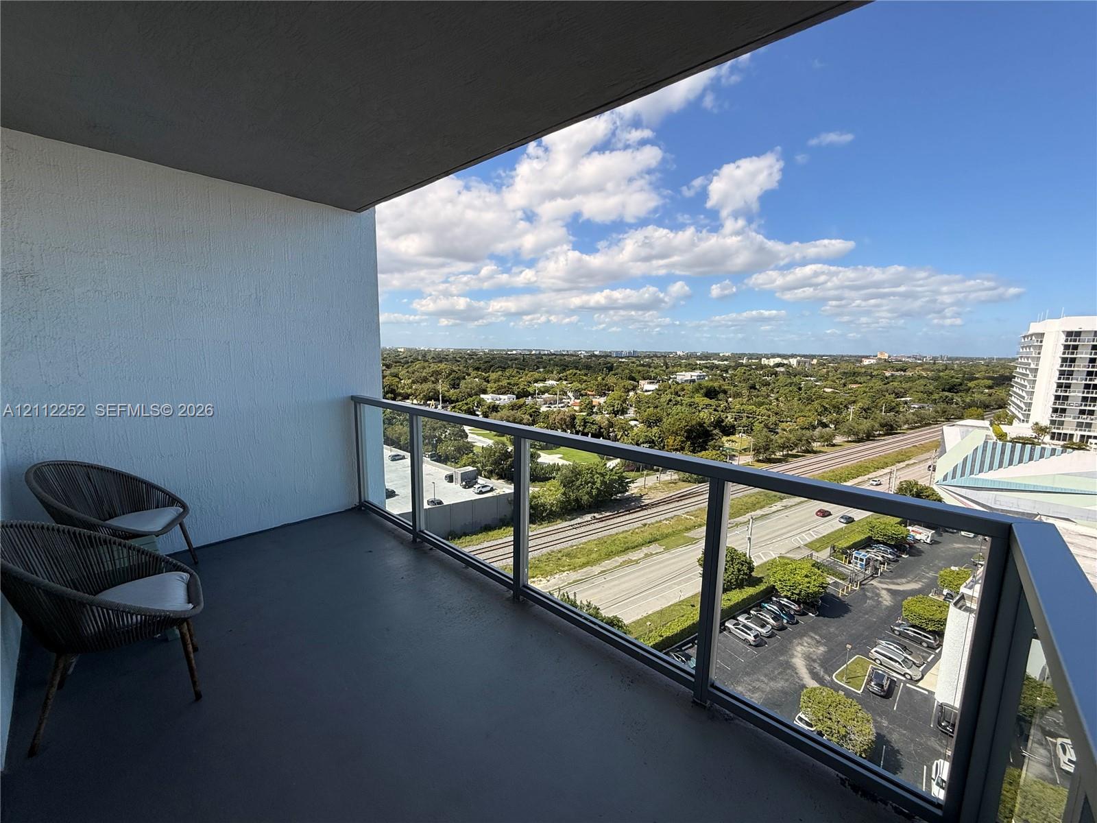 Covered balcony featuring concrete flooring and a glass-paneled railing