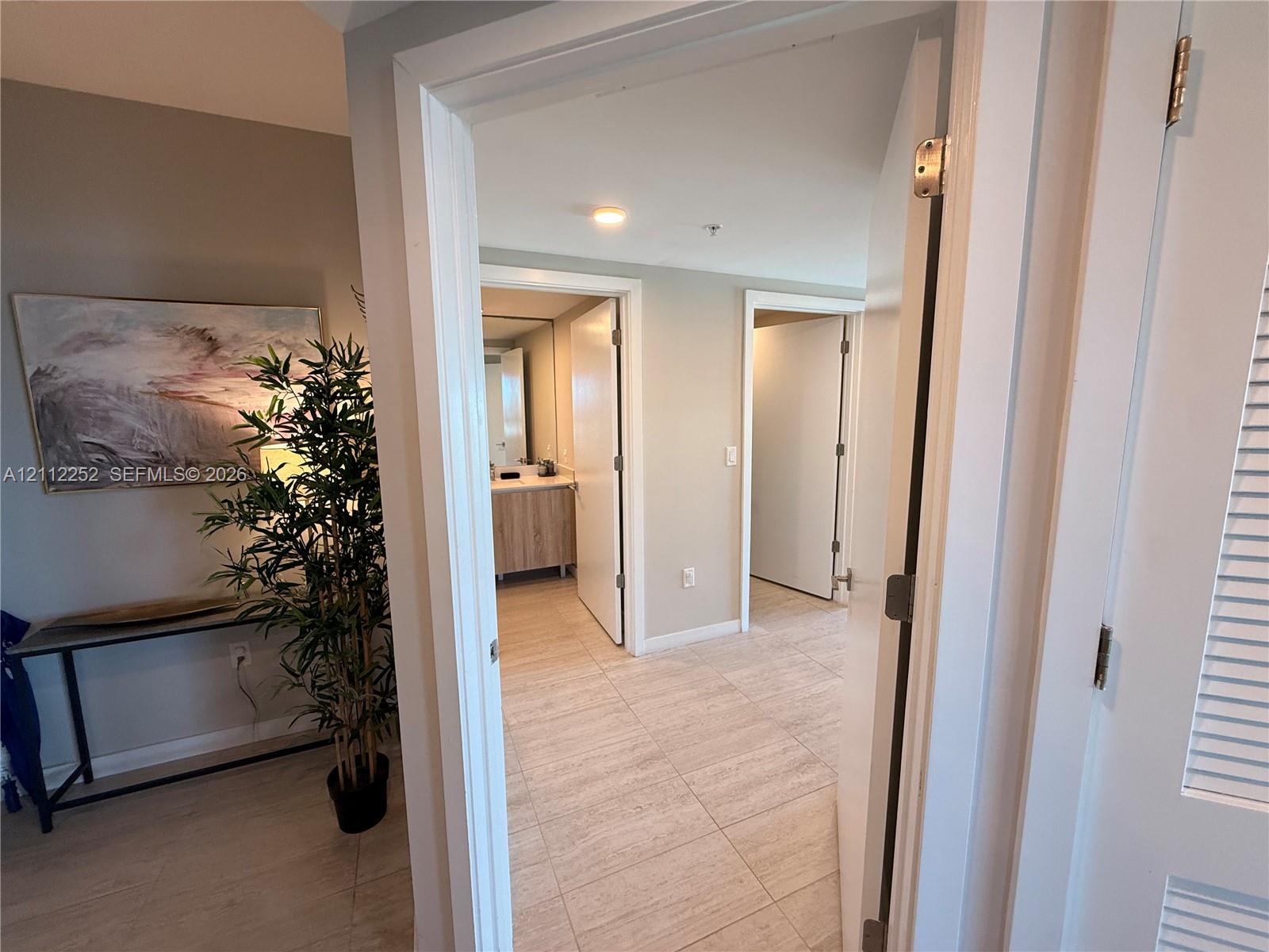 Ceramic tile flooring, white-finished interior doors with brushed metal hardware, and louvered closet doors