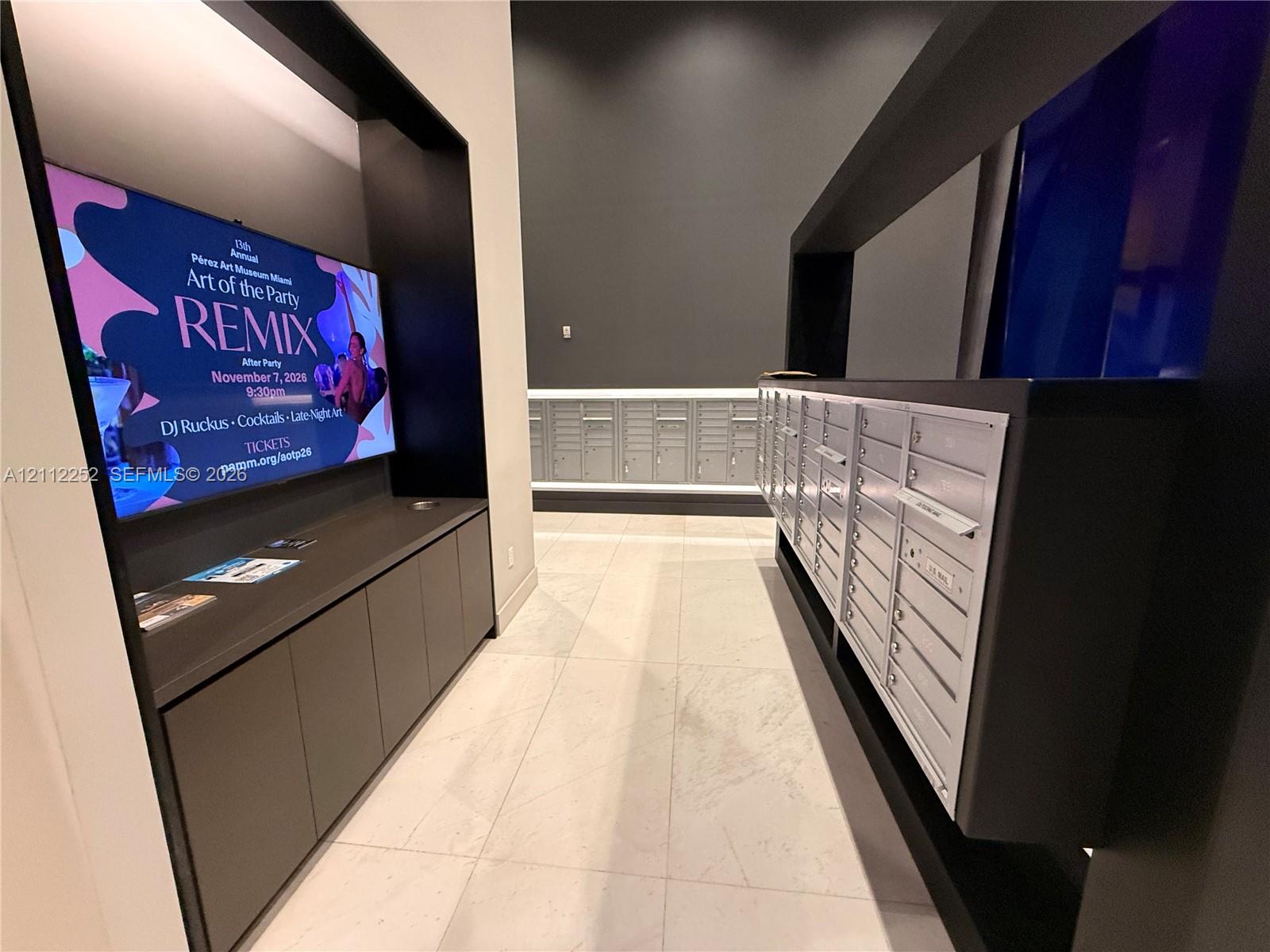 Mail center featuring integrated metallic mailboxes, built-in matte black cabinetry, and large-format tile flooring