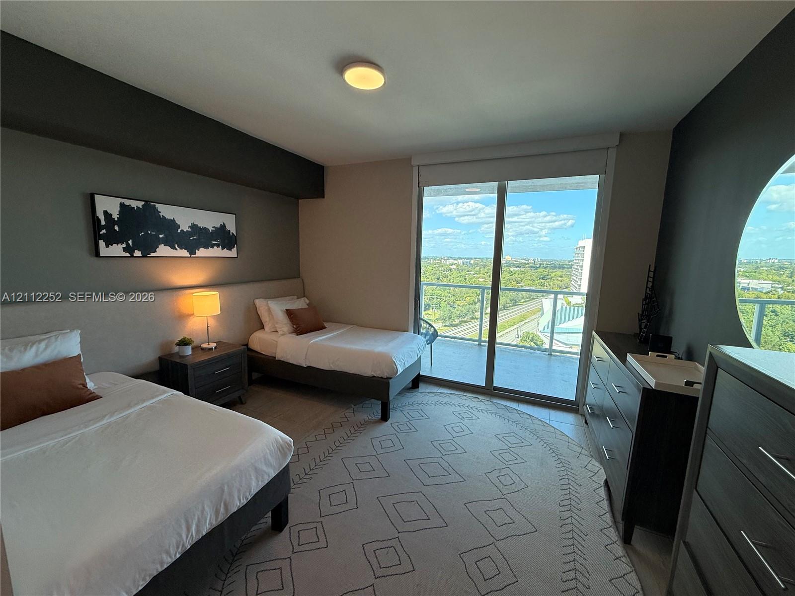 Sliding glass doors opening to a private balcony, large circular window, and neutral wall-finish flooring