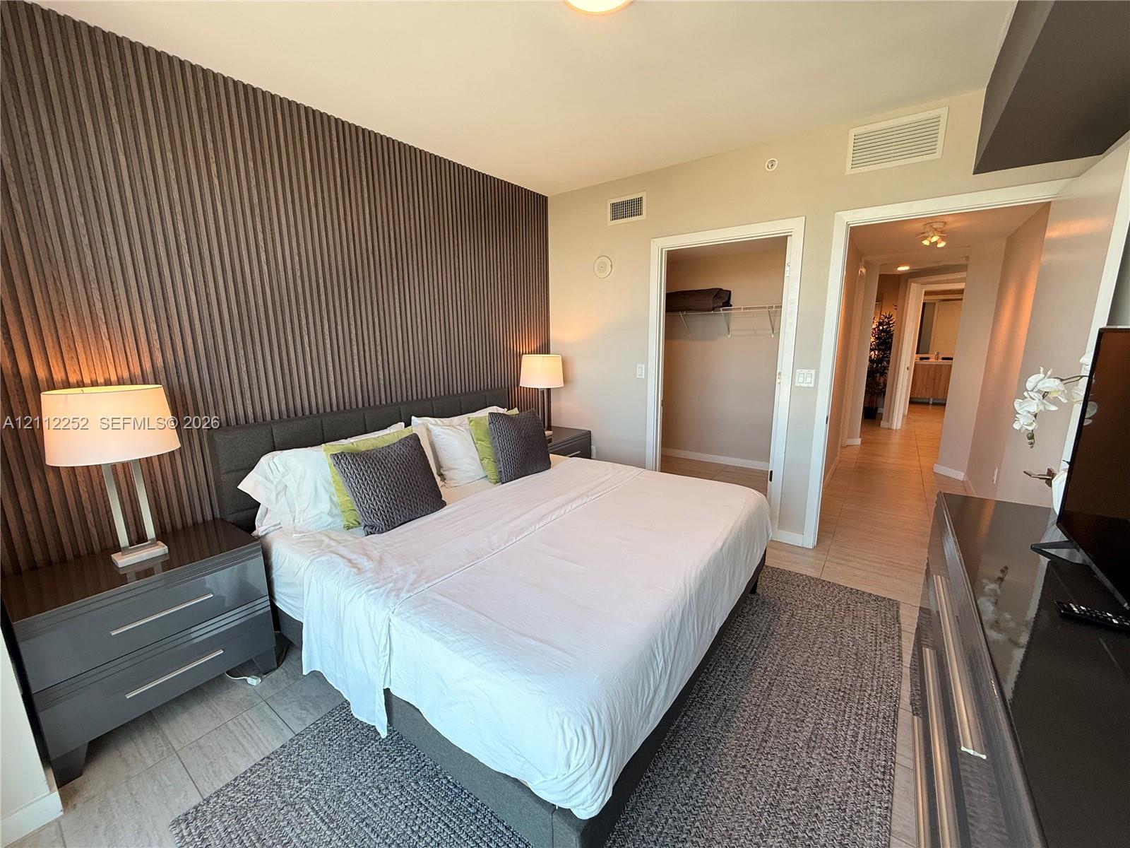Textured vertical wall paneling, tile flooring, and a built-in reach-in closet