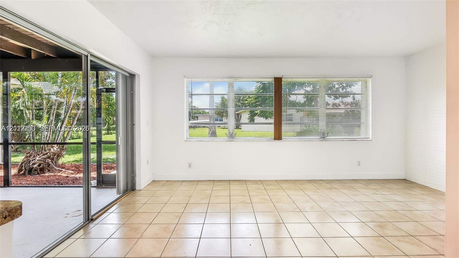 Interior space featuring large-format ceramic tile flooring, expansive horizontal sliding windows, and a set of glass sliding doors providing external access