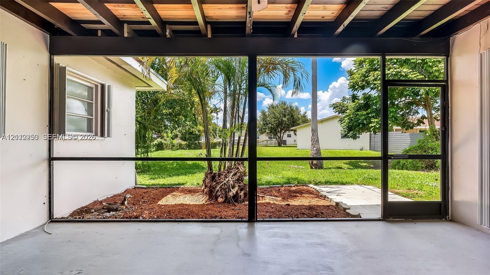 Screened-in patio with concrete flooring, exposed wood-beam ceiling, and full-height mesh enclosures