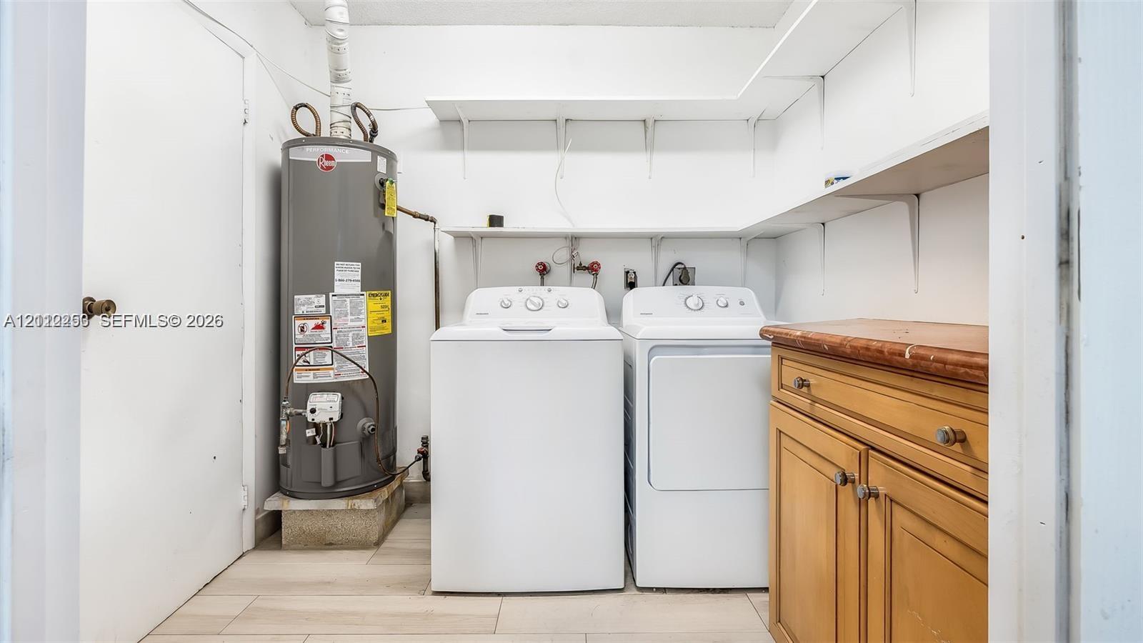 Laundry Room featuring wood-cabinetry, stone-style countertop, tiered white shelving, and tile flooring