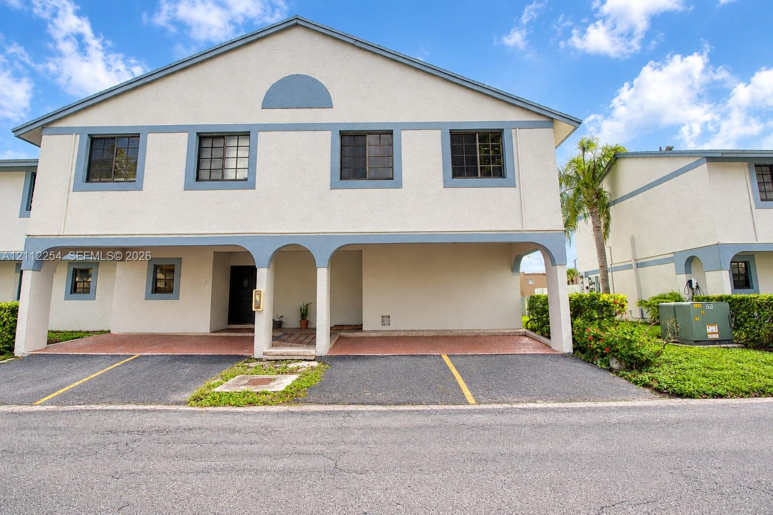 Two-story stucco exterior with arched portico, covered parking, and multi-pane windows Two-story stucco exterior with arched portico, covered parking, and multi-pane windows