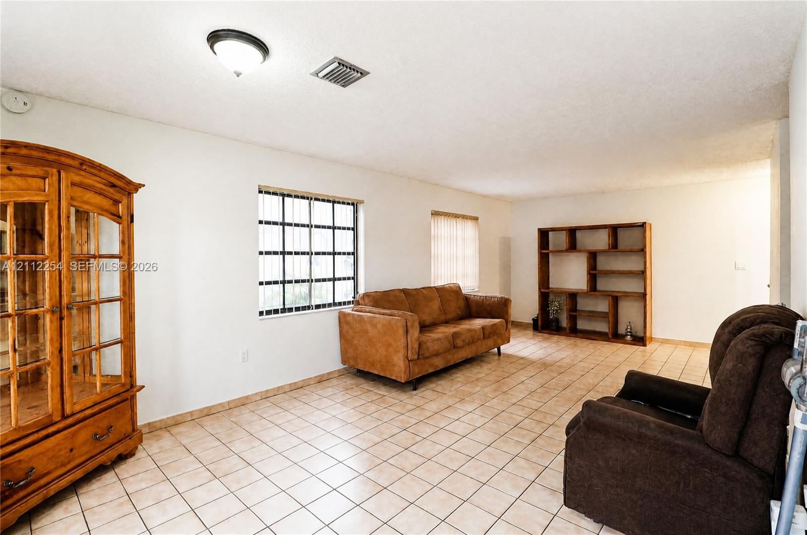 Interior space featuring neutral-toned tile flooring, recessed window grids, and built-in wooden shelving