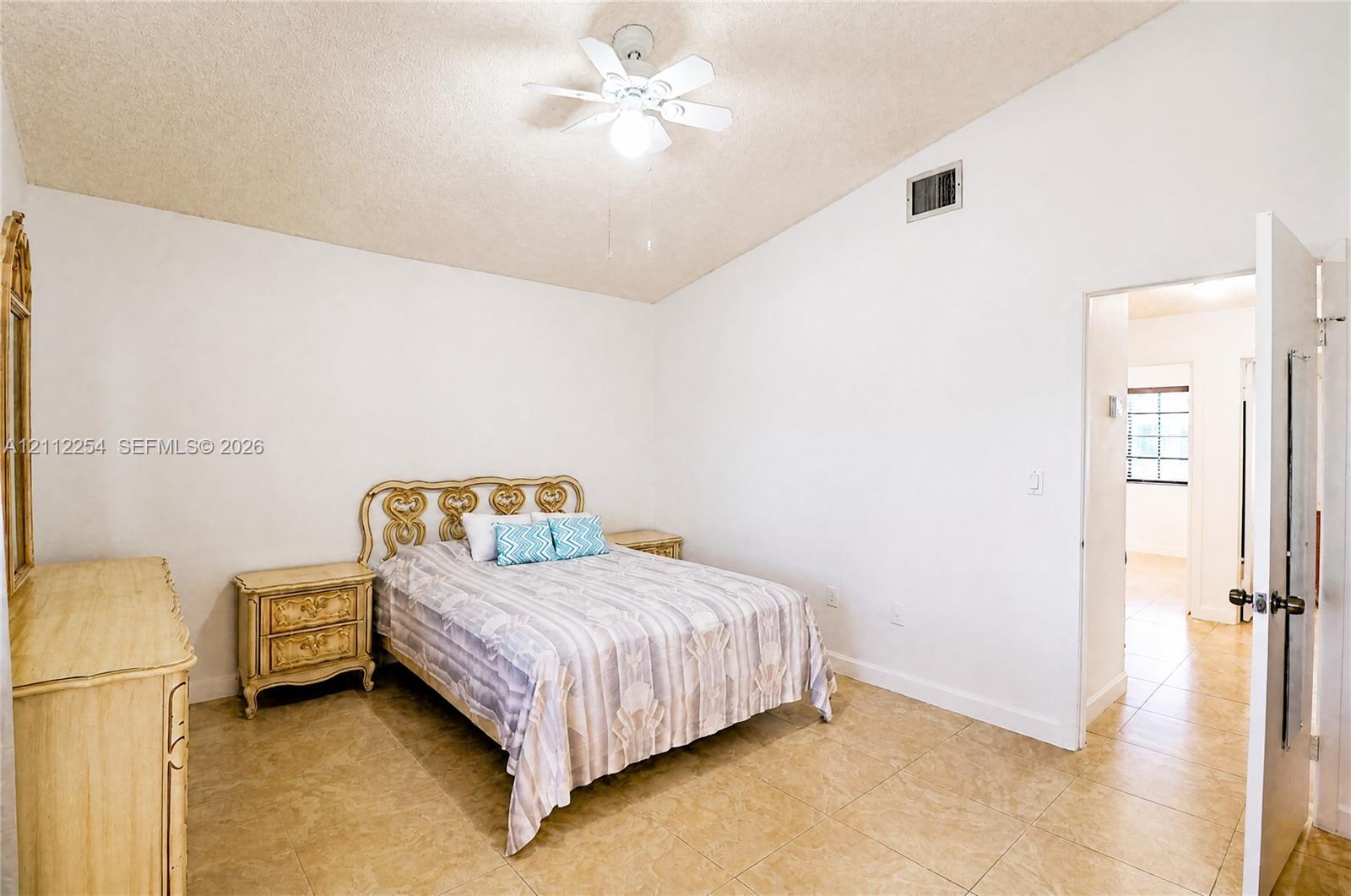 Vaulted ceiling, ceiling fan with integrated lighting, and stone-finish tile flooring
