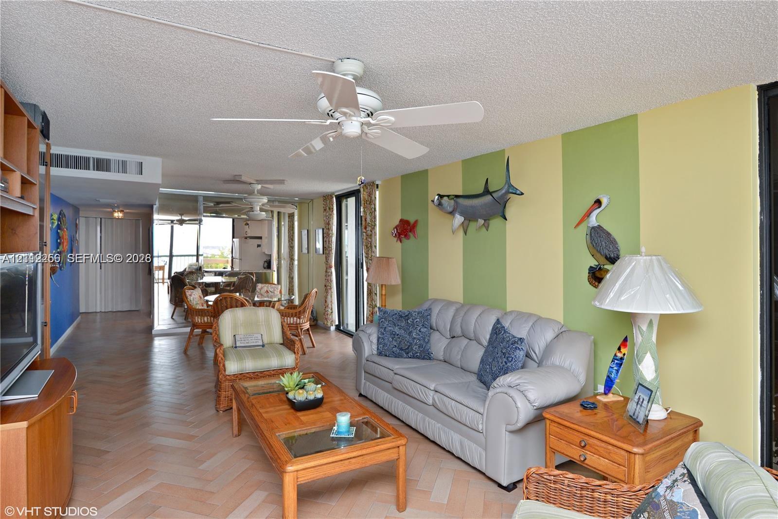 Herringbone-patterned wood-finish flooring, ceiling-mounted paddle fans, and floor-to-ceiling glass sliding doors