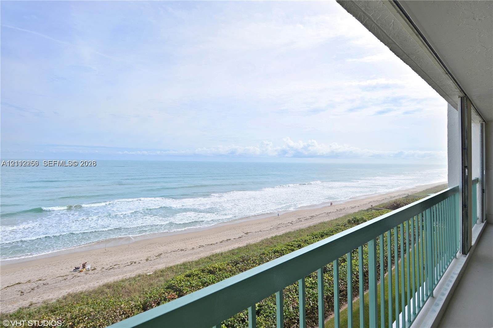 Covered balcony with a protective metal railing, featuring direct exposure to the ocean coastline