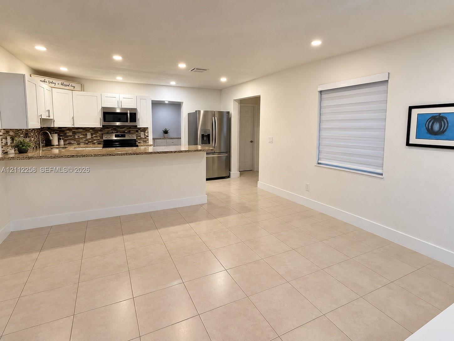 Kitchen featuring white cabinetry, stone-surface countertops, mosaic tile backsplash, recessed lighting, and large-format tile flooring