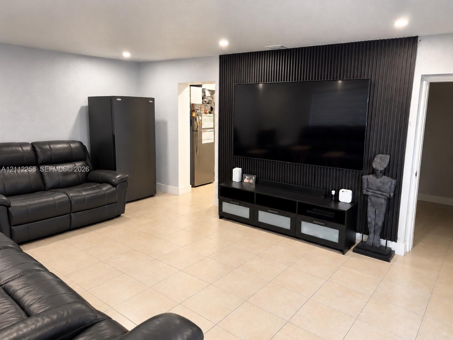 Textured black vertical-slat accent wall, tile flooring, and recessed ceiling lighting Textured black vertical-slat accent wall, tile flooring, and recessed ceiling lighting