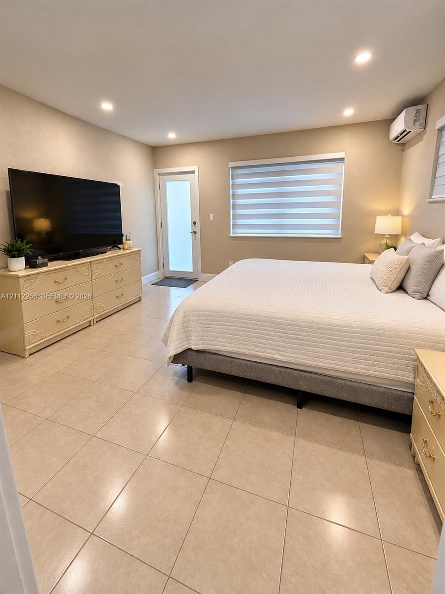 Neutral-toned ceramic tile flooring, recessed ceiling lighting, wall-mounted climate control unit, and window with adjustable light-filtering shade Neutral-toned ceramic tile flooring, recessed ceiling lighting, wall-mounted climate control unit, and window with adjustable light-filtering shade
