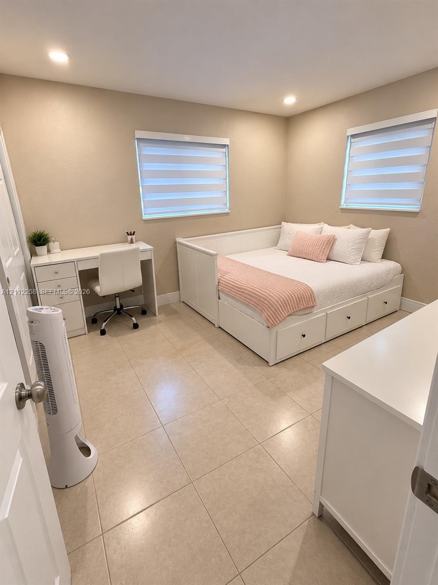 Neutral-toned interior featuring oversized tile flooring, recessed lighting, and dual windows equipped with zebra-style blinds Neutral-toned interior featuring oversized tile flooring, recessed lighting, and dual windows equipped with zebra-style blinds