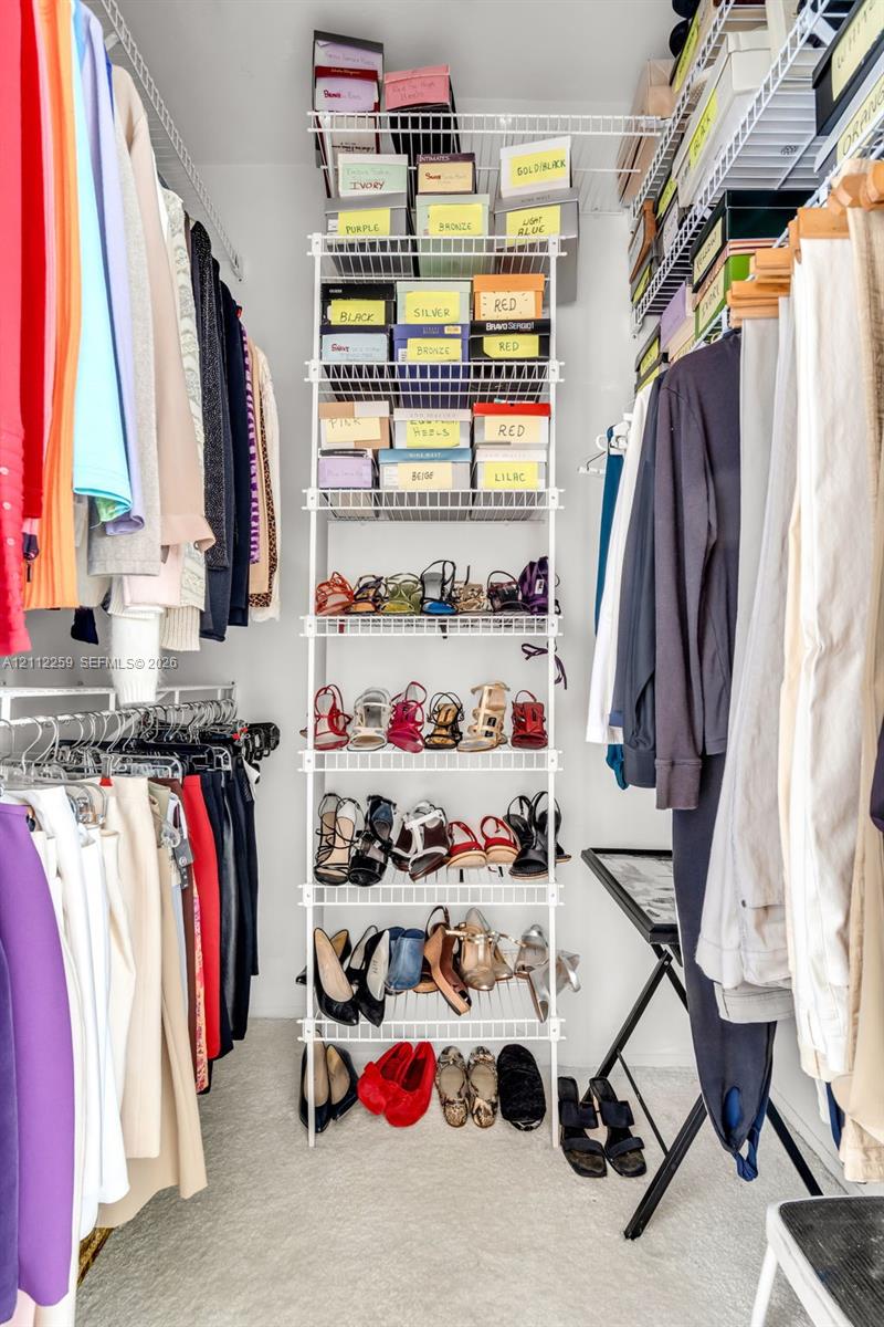 Walk-in closet featuring multi-tiered wire shelving and wall-to-wall hanging rods